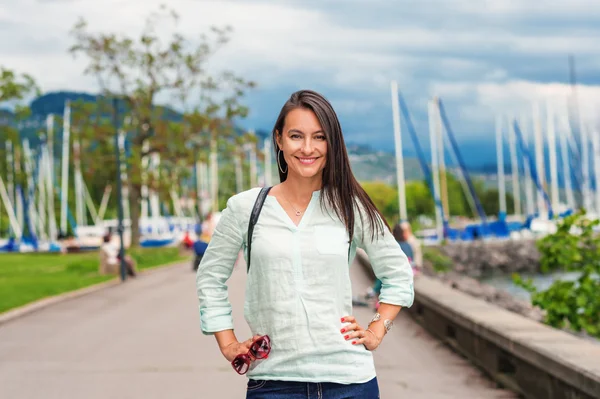 Junge brünette Frau mit Rucksack spaziert im Park — Stockfoto