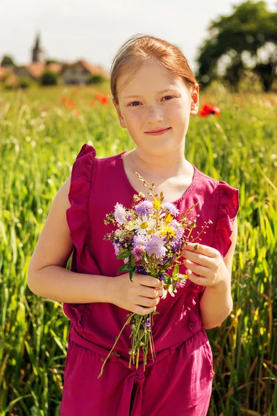 Retrato ao ar livre de adorável menina com buquê de flores silvestres — Fotografia de Stock