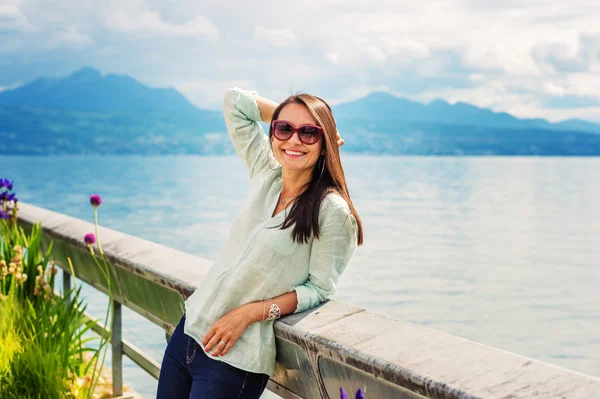 Porträt einer jungen brünetten Frau, die draußen am See ruht und eine Sonnenbrille trägt. Aufnahme am Genfer See, Schweiz — Stockfoto