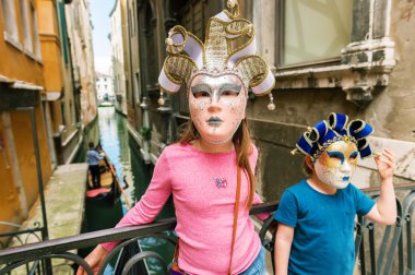 Ünlü Venedik Maske ile oynayan iki çocuklar. Küçük kız ve erkek Venedik, İtalya ziyaret etti. Küçük turistler Hatıra karnaval maskesi takmış