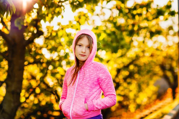 Ritratto all'aperto di una graziosa bambina di 8-9 anni al tramonto, con cappuccio rosa brillante — Foto Stock