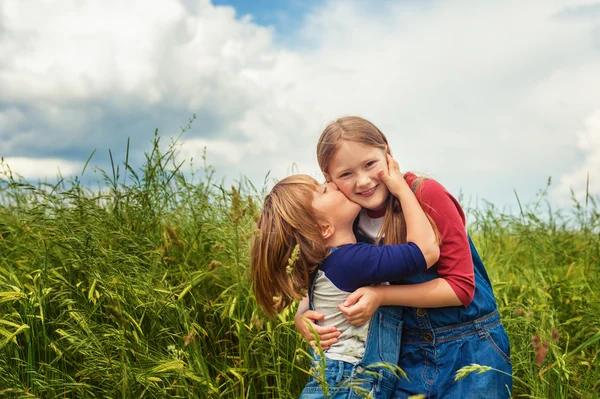 Dos niños adorables, niña y niño, jugando en el campo de trigo verde. Dulces niños divirtiéndose en verano. Hermano pequeño besando a su hermana — Foto de Stock