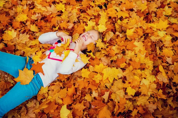 Ritratto autunnale di una graziosa bambina di 8-9 anni che gioca con foglie gialle nel parco — Foto Stock