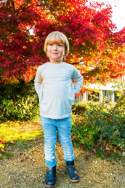 Outdoor-Herbst-Porträt eines netten kleinen Jungen von 4 Jahren an einem schönen sonnigen Tag, trägt beiges Top, hellblaue Jeans und Stiefel — Stockfoto