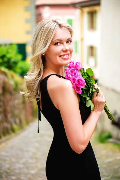 Portrait extérieur de belle femme blonde tenant un bouquet de roses roses — Photo