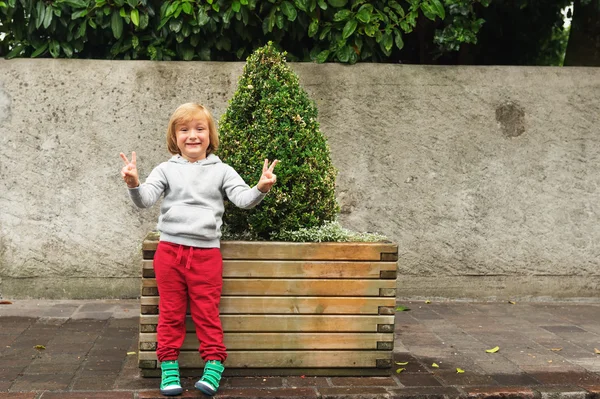 Ritratto di moda di adorabile bambino che indossa felpa grigia, allenamenti rossi e scarpe verdi — Foto Stock