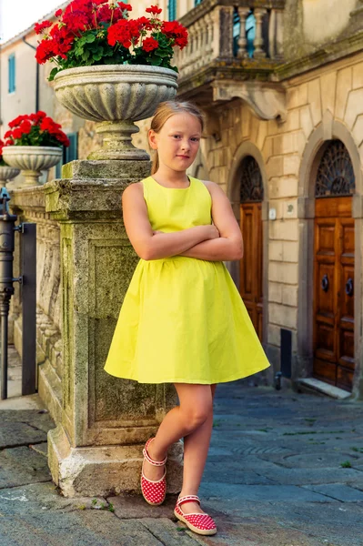 Retrato de moda al aire libre de una linda niña de 8-9 años en la antigua calle de Toscana, Italia. Niño preadolescente con vestido verde, brazos cruzados, imagen vertical — Foto de Stock