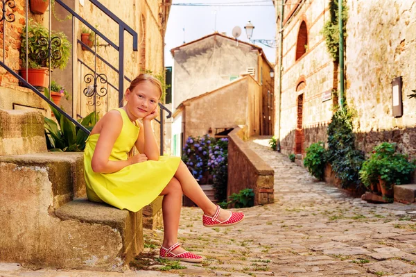 Douce petite fille de 8 ans assise sur des escaliers dans une petite vieille ville italienne en Toscane, Italie. Preteen mignon portant une robe verte et des chaussures rouges — Photo