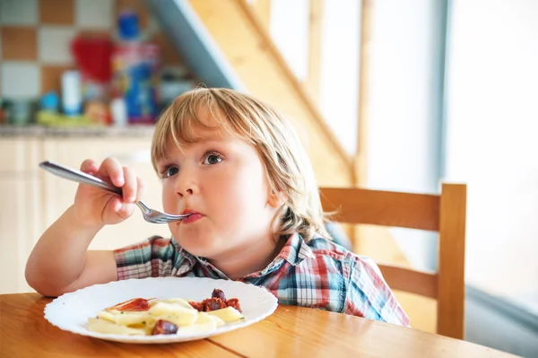 Imádnivaló kisgyermek fiú eszik ebédjét a konyhában, tévénézés — Stock Fotó