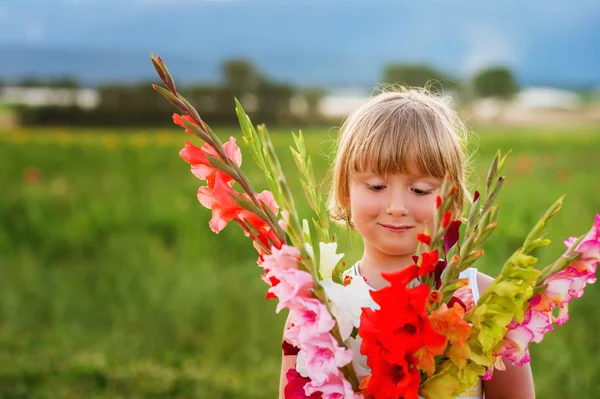 Piękny bukiet kwiatów gladiolas jasne i kolorowe, trzymając za ładny mały chłopiec — Zdjęcie stockowe