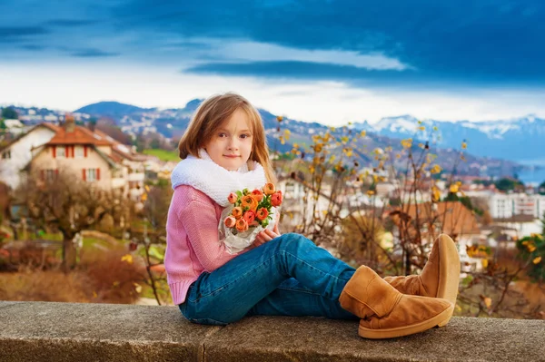 Outdoor portrait of a beautiful little girl with bouquet of spring flowers — Stock Photo, Image