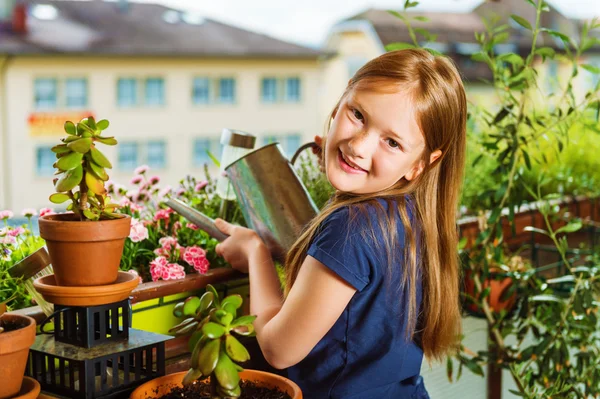 Adorable petite fille arrosant des plantes sur le balcon par une belle journée ensoleillée — Photo