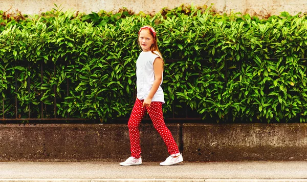Zewnątrz mody portret z ute mała dziewczynka 8-9 lat, idąc ulicą, noszenie spodni polkadot i białą koszulkę, stonowanych obrazów — Zdjęcie stockowe