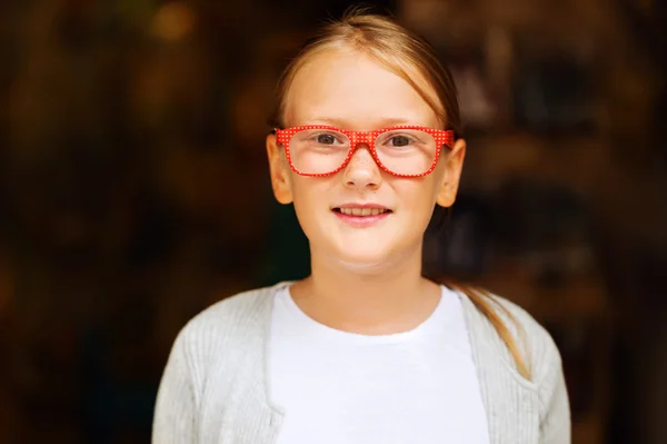 Portret van een schattig klein meisje in rode polka dot bril tegen donkere achtergrond — Stockfoto