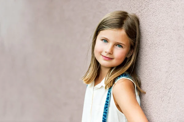 Close up retrato de uma menina bonito de 7-8 anos de idade inclinando-se para a parede rosa — Fotografia de Stock