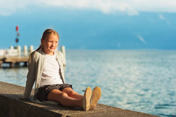 Niedliches kleines Mädchen, das sich bei Sonnenuntergang am Genfer See ausruht — Stockfoto