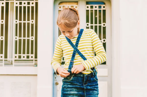 Outdoor portrait of a cute little girl wearing green t-shirt and denim skirt — Stock Photo, Image