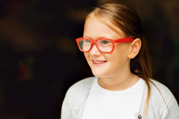 Ritratto di una graziosa bambina in occhiali a pois rossi sullo sfondo scuro — Foto Stock