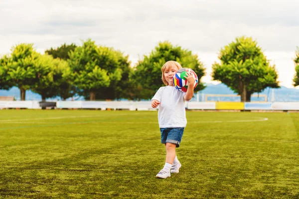 Adorable niño de 3 años jugando fútbol en el estadio —  Fotos de Stock
