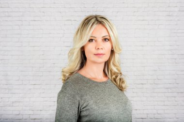 Beyaz duvara karşı genç sarışın bir kadın portresi