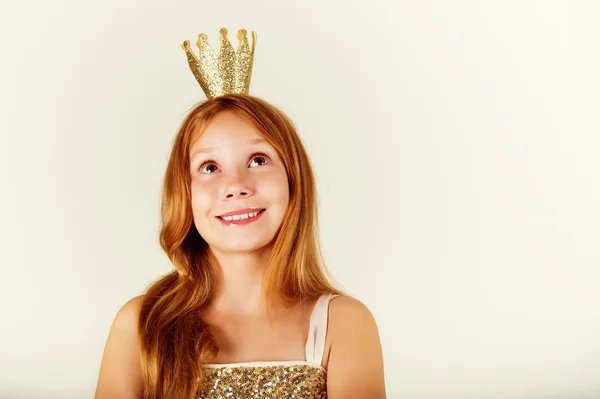 Pretty little girl with beautiful red hair looking up. Little princess with a crown on her head. Kids fashion. toned image — Stock Photo, Image