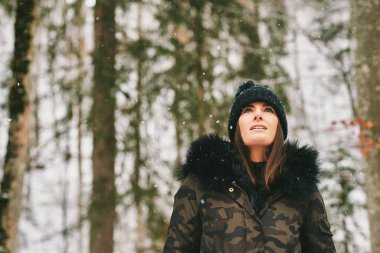 Mutlu genç bayanın mevsimsel açık hava portresi. Kışın güneşli günlerinde ormanın tadını çıkarıyor.