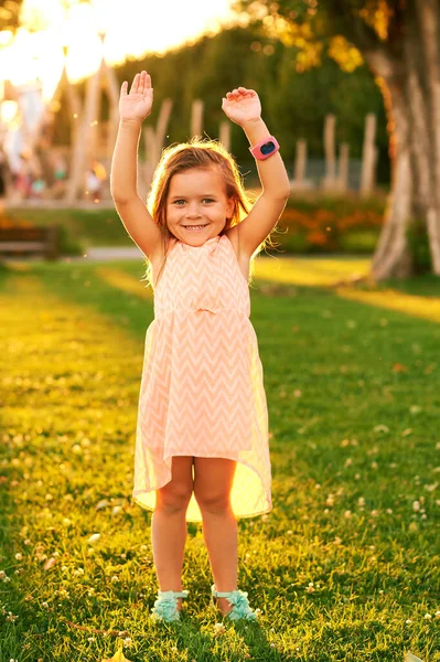 夏の公園で遊んで愛らしい3 4歳の少女の屋外肖像画 腕を上げ スマートウォッチを身に着けて 明るい緑の芝生の上で美しい日差し — ストック写真