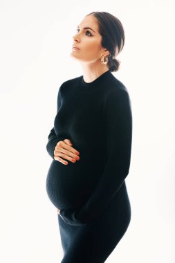 Beyaz arka planda poz veren, siyah kaplumbağa yakalı, harika bir kadının hamile portresi. 