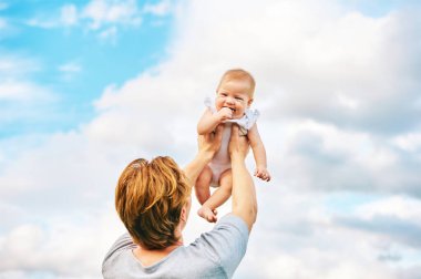 Mutlu genç baba dışarıda sevimli bir kızla oynuyor, aile hayatı, baba çocuğu havada tutuyor.