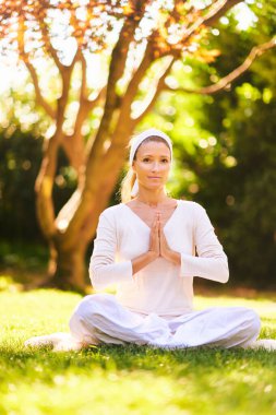 Yeşil güneşli bahçede ya da parkta meditasyon yapan güzel olgun bir kadın. Sağlıklı bir yaşam tarzı.