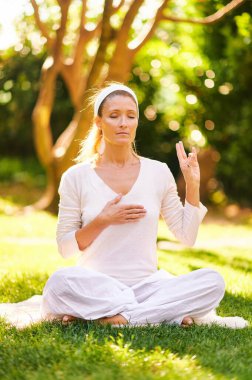 Güzel olgun bir kadın yeşil güneşli bahçede meditasyon yapıyor, sağlıklı bir yaşam tarzı var.