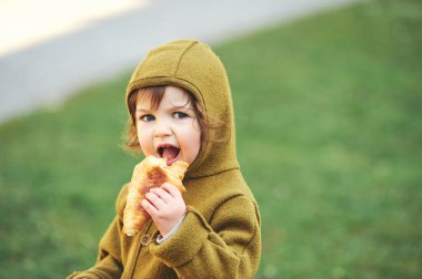 Açık hava portresi. 1-2 yaşlarında ay çöreği yiyen bir çocuk.