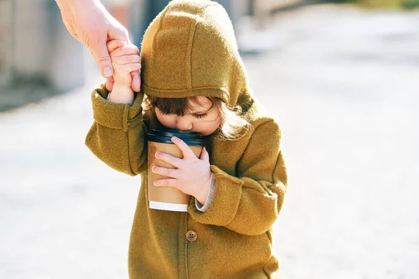 外を歩く面白い幼児の子供 紙コップを奪うから飲む 母親の手を握って — ストック写真