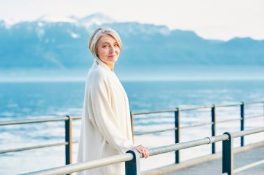 Güzel orta yaşlı kadın, kış gölü ve dağların muhteşem manzarasına hayran.