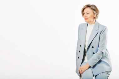 Beyaz arka planda poz veren orta yaşlı bir kadının stüdyo portresi