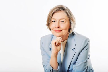 Beyaz arka planda poz veren orta yaşlı bir kadının stüdyo portresi