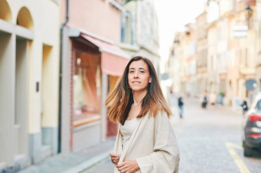 Orta yaşlı Latin bir kadının açık hava portresi. Sokakta yürüyor, kameraya bakmak için geri dönüyor.