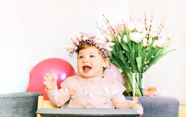 椅子に座って花のヘッドバンドを身に着けている可愛い赤ちゃんの春の肖像画 — ストック写真