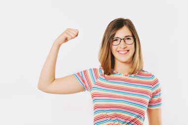 Gökkuşağı tişörtü ve gözlük takarak ne kadar güçlü olduğunu gösteren mutlu genç bir modelin stüdyo portresi.