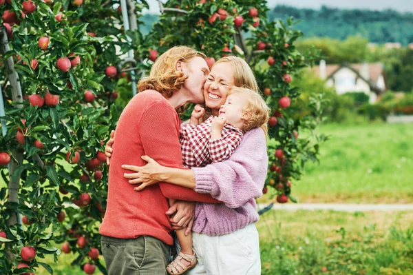 快乐的年轻家庭与蹒跚学步的小女孩的户外肖像 在苹果园享受美好的一天 — 图库照片