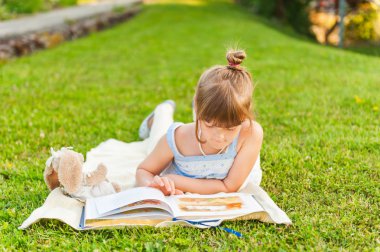 Açık havada dinlenme ve bir güzel yaz akşamı bir kitap okuma sevimli küçük kız portresi