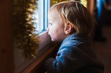 Noel zamanda penceresine bakarak şirin yürümeye başlayan çocuk