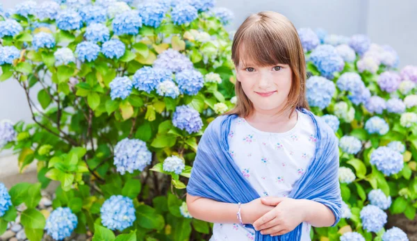 Yaz çiçekler arasında oturan küçük şirin bir kız portresi — Stok fotoğraf