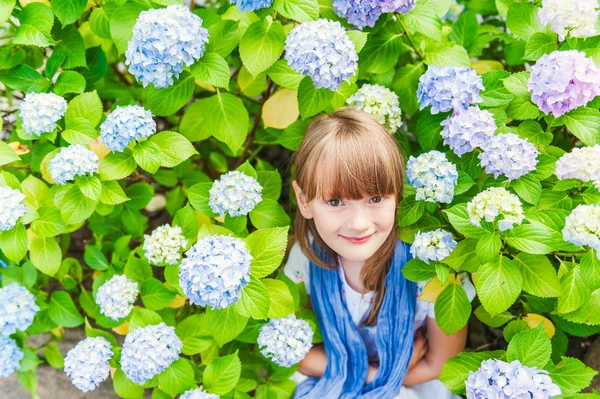 Summer portrait of a cute little girl sitting between flowers — Stock Photo, Image