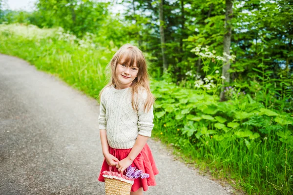 Portrait of a cute little girl with basket with flowers — Stock Photo, Image