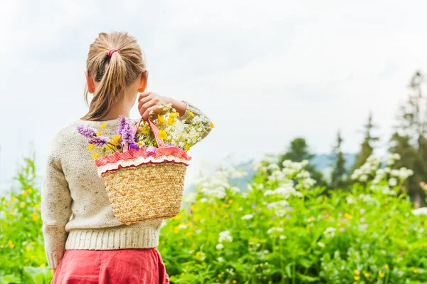 Porträtt av en söt liten flicka med korg med blommor — Stockfoto