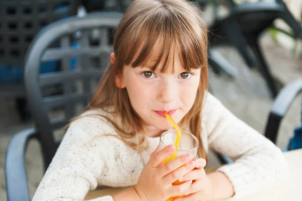 Außenporträt eines süßen kleinen Mädchens, das in einem Café Saft trinkt — Stockfoto