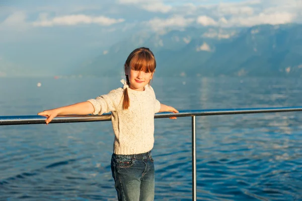 Retrato al atardecer de una linda niña al lado de un hermoso lago, con jersey de punto beige y jeans — Foto de Stock