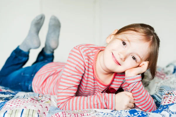 Schönes kleines Mädchen, das auf einem Bett liegt — Stockfoto