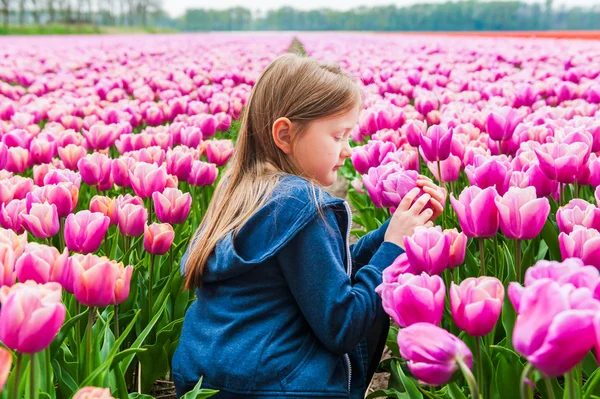 Милая маленькая девочка играет с тюльпанами в прекрасный весенний день — стоковое фото